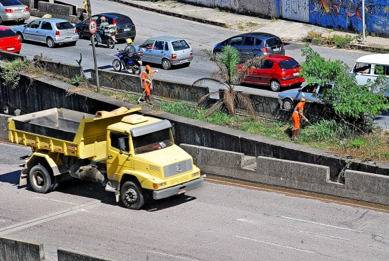 Caminhão amarelo trafegando em avenida movimentada de Belo Horizonte