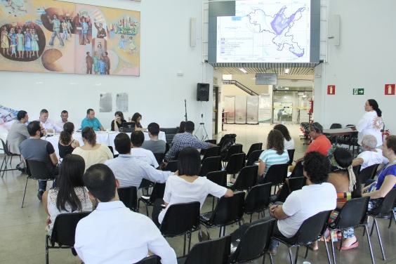 Parlamentares compõem mesa de reunião. Público ocupa cadeira a frente. Painel mostra mapa da região metropolitana de BH