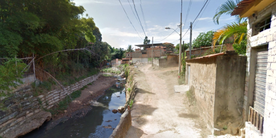 rua sem asfaltamento, ao lado de córrego urbano