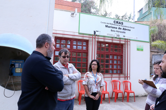 Comitiva em visita ao Cras Mariano de Abreu. Pessoas conversam e placa com o nome da unidade ao fundo