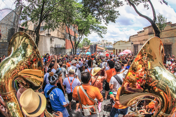 bloco de rua, foliões caminham pela rua, instrumentos de sopro em destaque