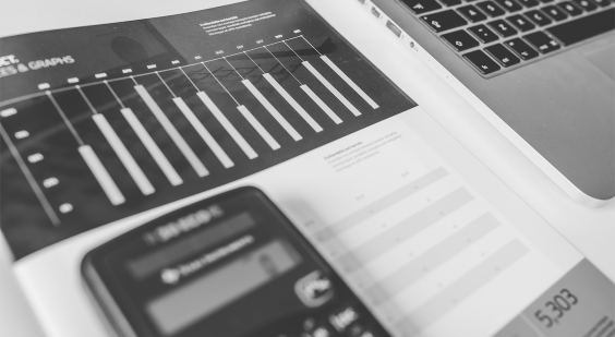 calculadora sobre papel exibindo gráfico de execução financeira mensal. Notebook ao lado