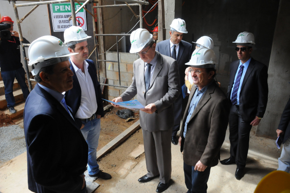 Homens de capacete, terno e gravata visitando obras