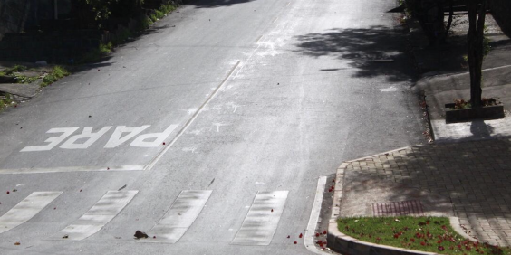 Sinalização horizontal no cruzamento de vias. Faixa de pedestre e inscrição de PARE pintadas no asfalto