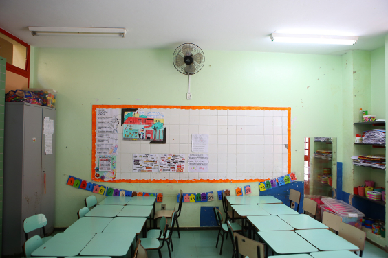 Sala de aula com carteiras enfileiradas. Ao fundo, o quadro branco. A sala está vazia 