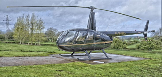 Helicóptero pousado em local cercado de grama.