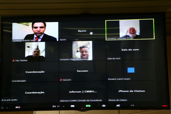 Telão com a imagem de três dos cinco vereadores participantes da reunião