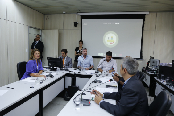 Seis parlamentares em reunião, sentados à mesa, acompanhados por dois assessores da Câmara, de pé, ao fundo