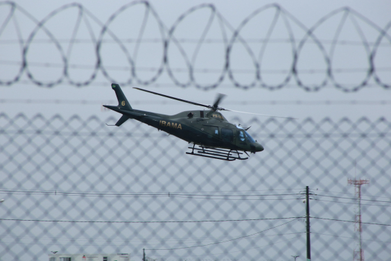 Imagem de um helicóptero no ar. é possível ver a cerca de segurança no local 