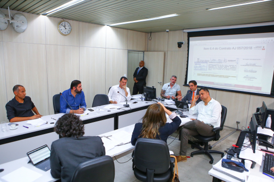 Imagem de participantes em torno da mesa. 