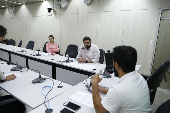 Três vereadores reunidos, sentados à mesa. 