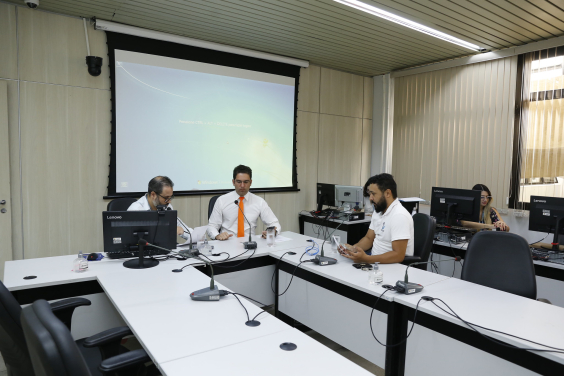 Três vereadores participam de reunião, sentados à mesa.