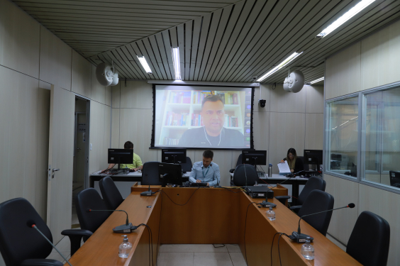 Imagem do Plenário Camil Caran. Um telâo ao alto mostra a imagem do vereador Irlan Melo, que participa da reunião remotamente