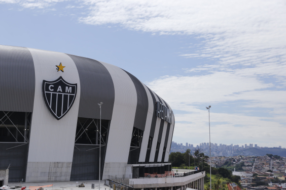 Foto da Fachada da Arena MRV, com a cidade ao fundo, durante o dia.