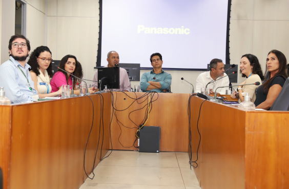 Imagem dos participantes da reunião sentados em uma mesa em formato U 