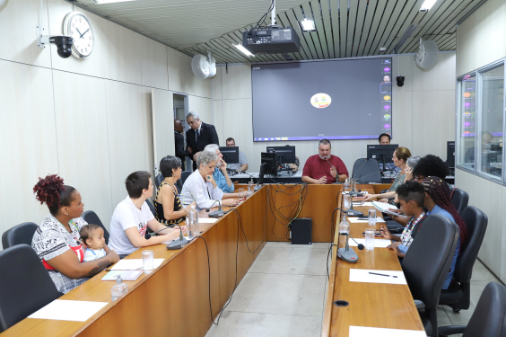 IMagem do Plenário Camil Caram durante a reunião. Pedro Patrus está sentado na cabeceira da mesa repleta de convidados