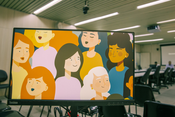 Sala da CMBH com telão mostrando arte gráfica com ilustrações de diversas mulheres de etnias diferentes.