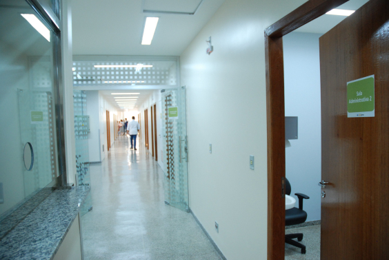 Corredor de posto de saúde, com homem de costas ao fundo 