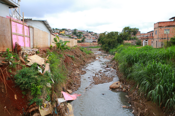 vista de córrego com despejo de resíduos em ambiente urbano