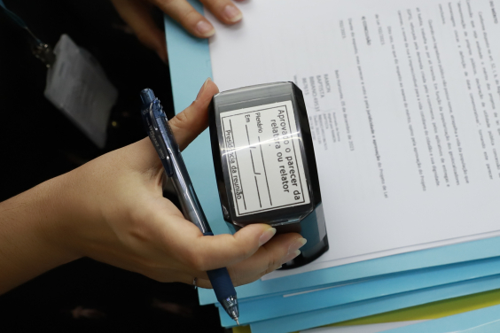 Mão segurando carimbo em cima de documento