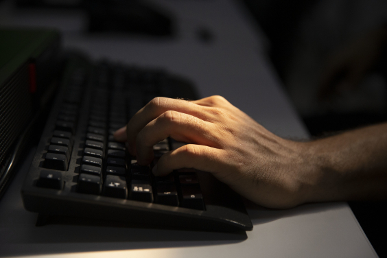 close nas mãos de pessoa digitando em teclado e computador
