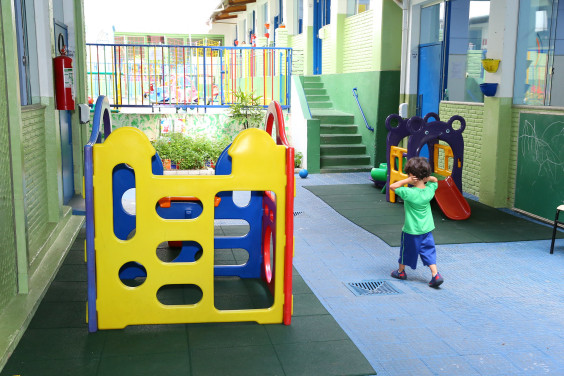 Criança com as mãos nos ouvidos anda em corredor de escola