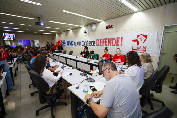 Vereadores e convidados no Plenário Helvécio Arantes, com faixas afixadas nas paredes