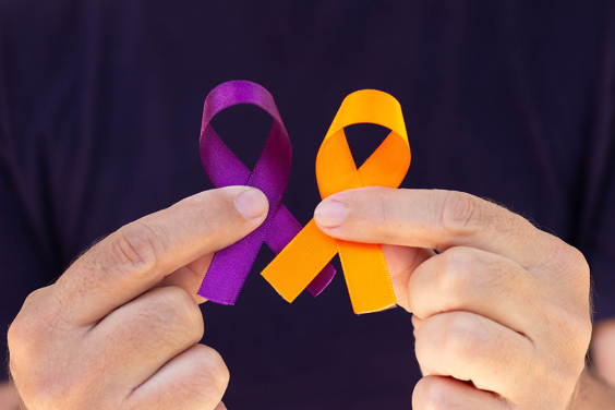 close nas mãos de pessoa segurando laços nas cores roxo e laranja
