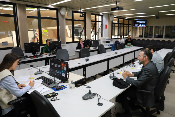 Imagem dos participantes da reunião sentados em torno de uma mesa em formato de U