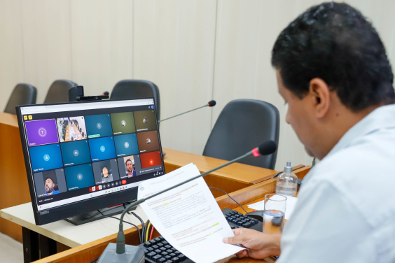 Vereador presidente da reunião conjunta em frente a tela com demais vereadores para apreciar parecer