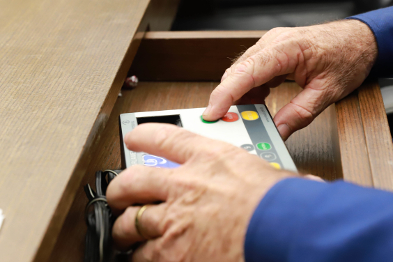 mãos de parlametar operando terminal de votação