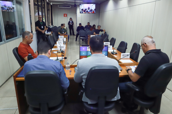 Vereadores reunidos durante audiência pública com cadeiras vazias de convidados ausentes