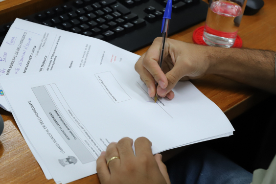 Vereador assina documento durante reunião da comissão de legislação e justiça da CMBH