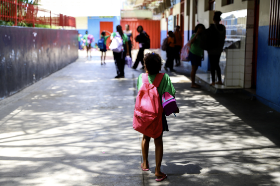 Criança com mochila de costas em ambiente escolar