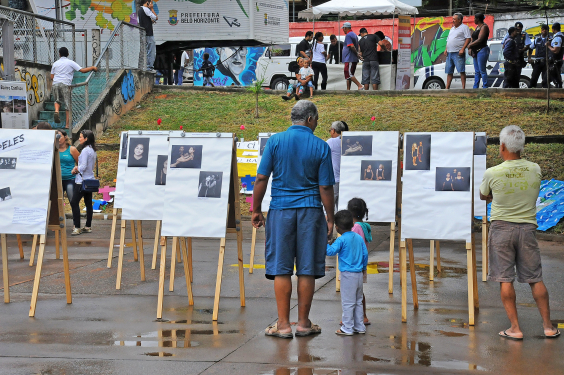 Adultos e crianças observam obras de arte em espaço público