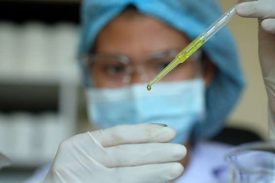 Profissional de saúde de máscara pinga sangue em recipiente