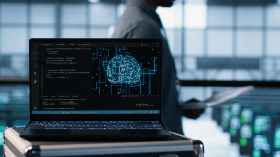 Computador em primeiro plano, com pessoa passando atrás