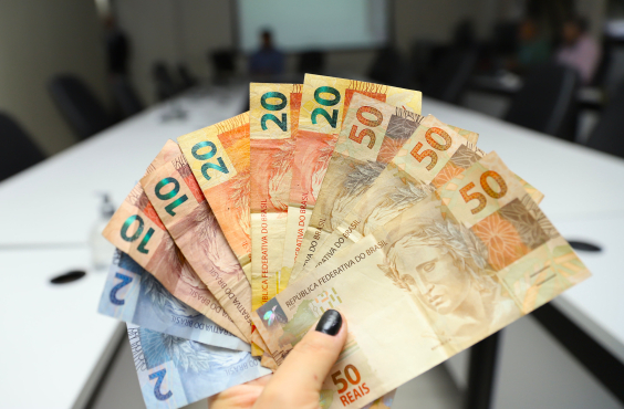 Pessoa segura várias notas de 20, 50 e 2 reais