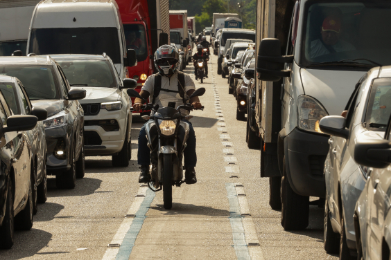 Motociclista trafega em faixa preferencial para motos, demarcada por linhas azuis, na capital paulista
