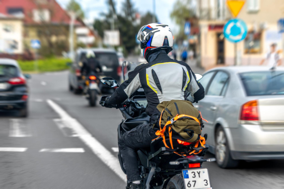 Motociclista trafega em rua de cidade