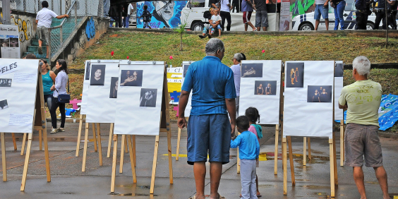 Adultos e crianças observam obras de arte em espaço público