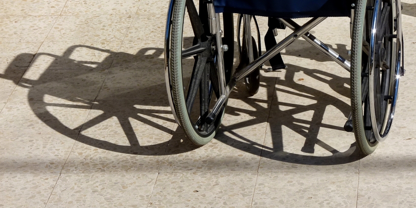 Imagem de uma cadeira de rodas, colocada de costas para o espectador