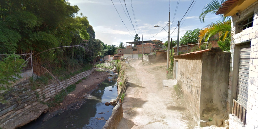 rua sem asfaltamento, ao lado de córrego urbano