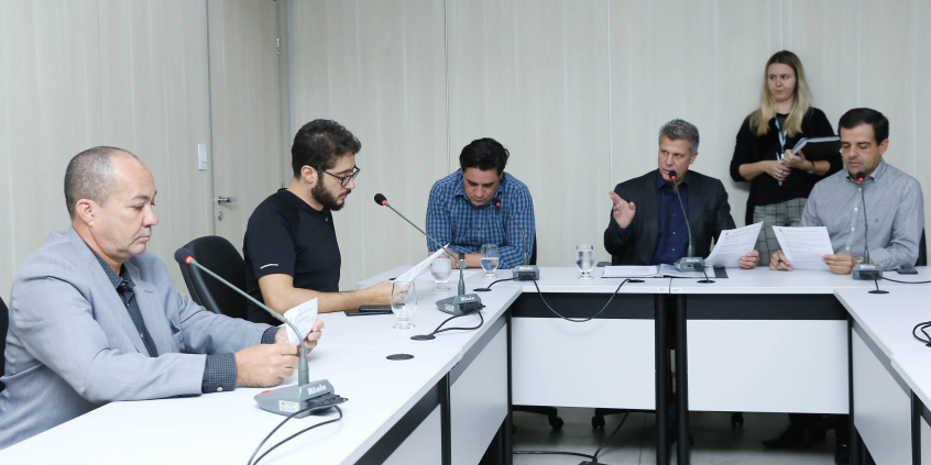 Os cinco integrantes da Comissão de Administração Pública sentados na Mesa do Plenário Helvécio Arantes apreciam a pauta da 18ª reunião ordinária