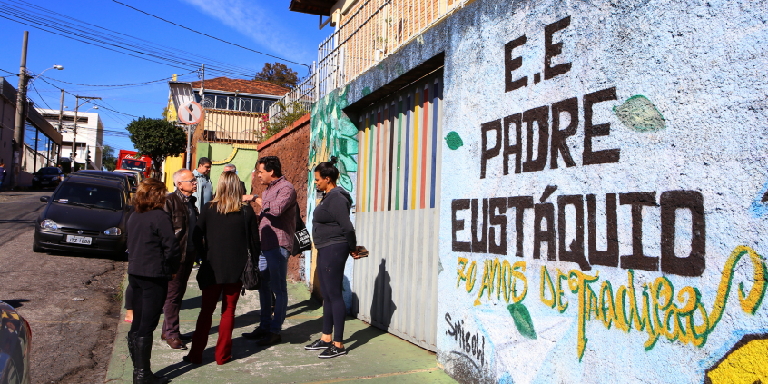 Fachada da Escola Estadual Padre Eustáquio. Comitiva na calçada.