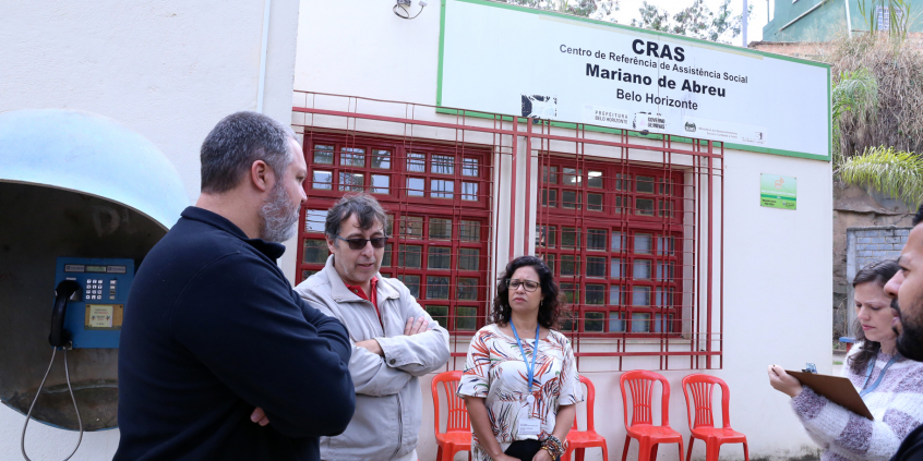 Comitiva em visita ao Cras Mariano de Abreu. Pessoas conversam e placa com o nome da unidade ao fundo