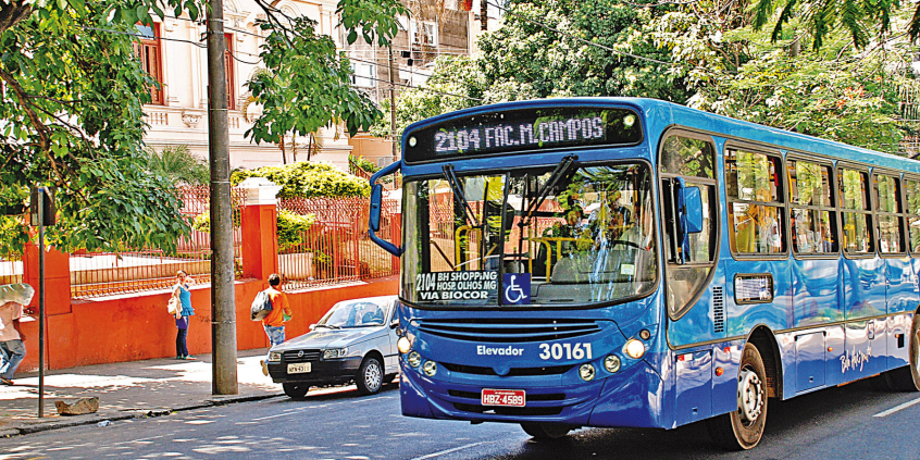 ônibus azul com os dizeres "2014 Fac Milton Campos" circula na cidade ,durante o dia.