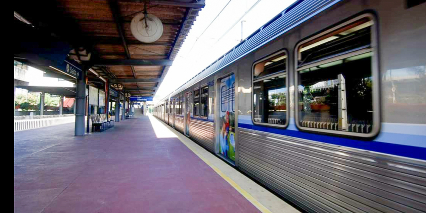 Plataforma de metrô com trem parado, de portas fechadas, durante o dia
