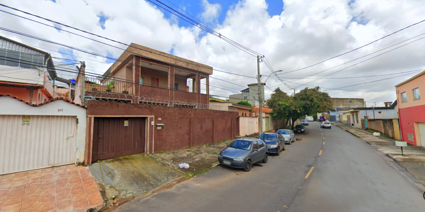 Foto de rua residencial, com mão dupla, casas e  cinco carros estacionados à esquerda, durante o dia