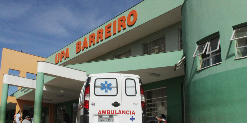 Fachada da UPA Barreiro. Prédio pintado de verde com letreiro vermelho indicativo ao alto. Na entrada, há uma ambulância estacionada.